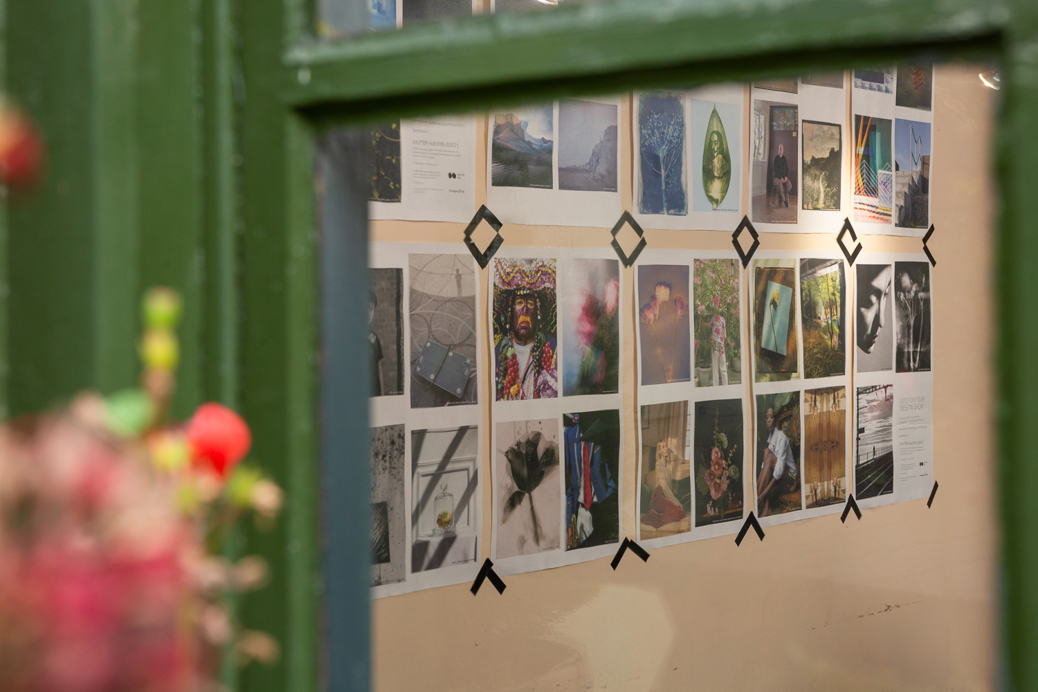 Photograph looking through a window into the Gallery Café at St. Margaret's House, showing an exhibition of photographs printed on newsprint,