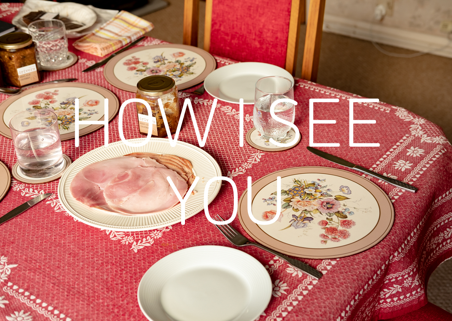 Graphic with a photograph of a table set for lunch with a pink tablecloth, plate of ham, a floral placemat, cutlery, a jar of chutney and glasses of water. Text in white in the middle says 'HOW I SEE YOU'